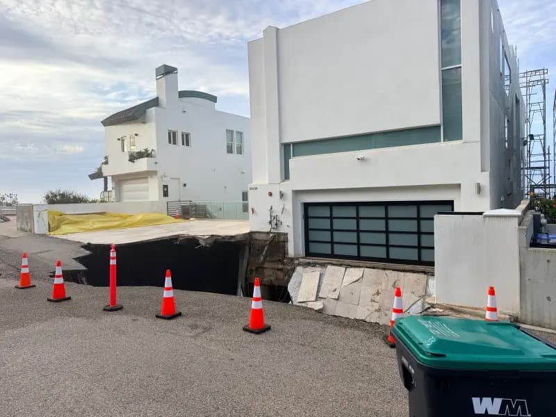 尼可拉斯凱吉豪宅前方路面嚴重塌陷,車道幾乎被巨大坑洞吞噬,現場已擺放交通錐警戒。(翻攝X@cinemaclt)